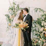 Phông nền đám cưới cổng hoa tươi tốt với cô dâu trong chiếc váy cưới lấy cảm hứng từ cổ điển cầm bó hoa cô dâu mùa xuân màu vàng và trắng