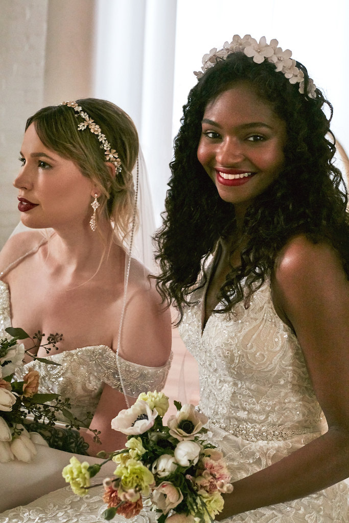 hai cô dâu mặc váy cưới với phụ kiện hoa và ngọc trai