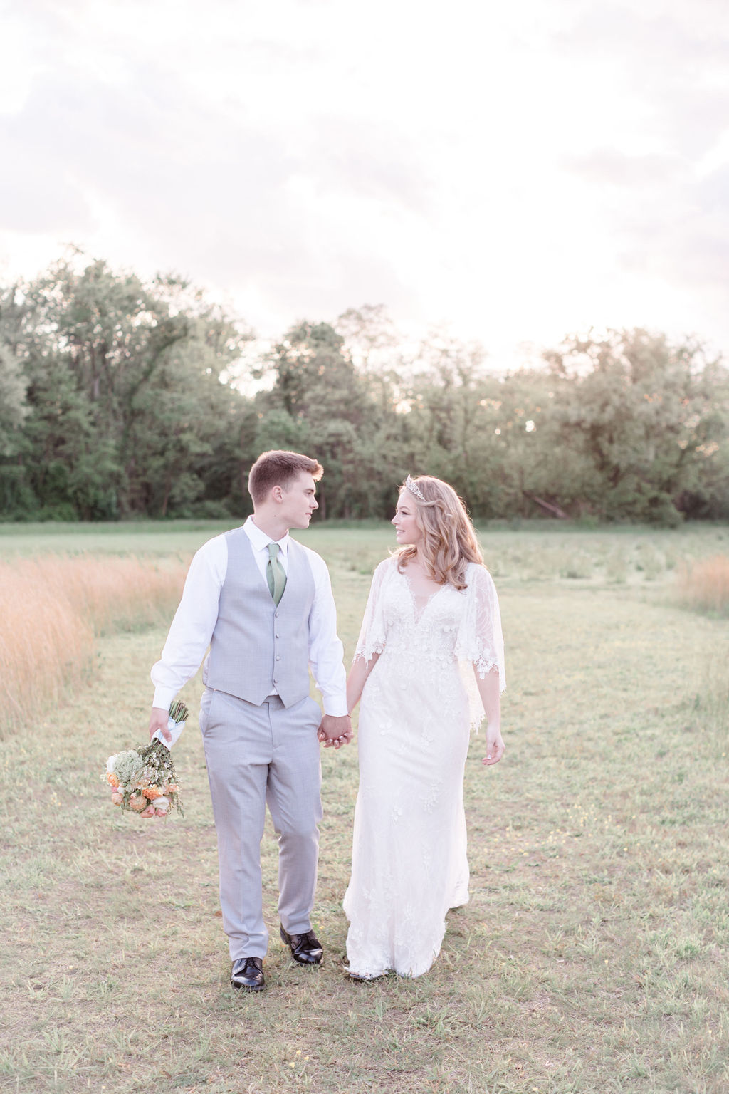 cô dâu và chú rể nắm tay nhau đi dạo trên cánh đồng trong đám cưới mùa xuân thơ mộng