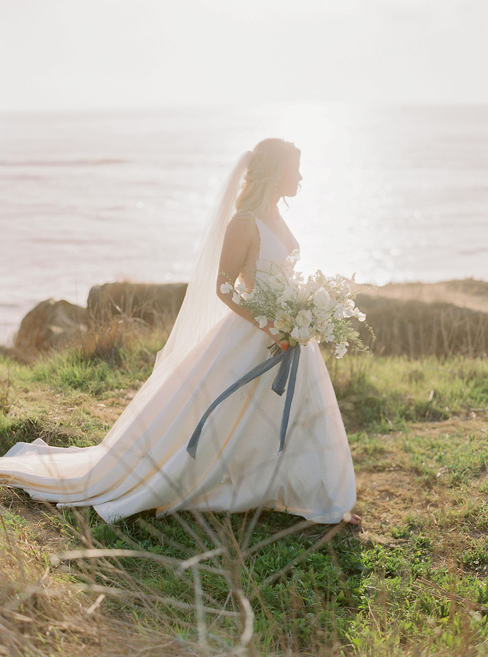 Chân dung cô dâu bỏ trốn ở Bờ biển Thái Bình Dương với bó hoa trắng hoang dã và dải ruy băng xanh bụi